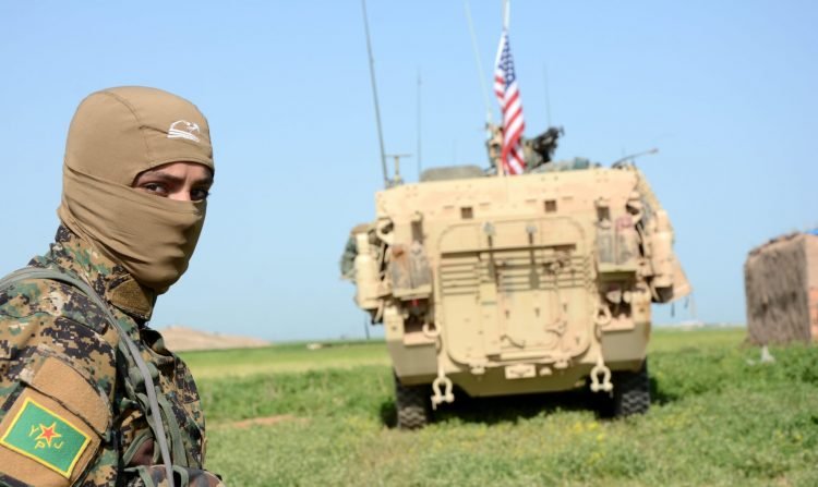 2017-04-29 00:00:00 epa05935402 A Soldier of the People's Protection Units (YPG) Kurdish militia stands next to a US eight-wheeled armored fighting vehicles, near al-Ghanamya village, al-Darbasiyah town at the Syrian-Turkish border, Syria, 29 April 2017. The Turkish army allegedly shelled several locations belonging to the YPG a day earlier with no casualties. EPA/YOUSSEF RABIE YOUSSEF